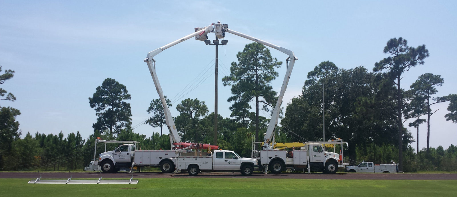 Several bucket trucks with linemen working on power poles.